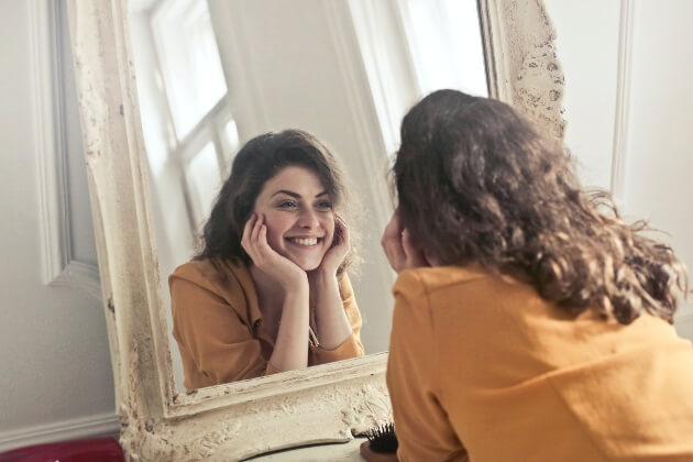 Woman admiring her smile in a mirror.